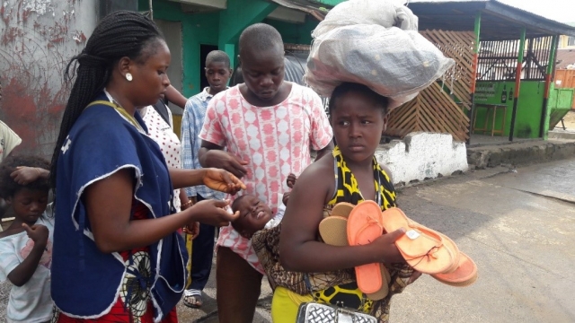 A vaccinator administring polio drops to a child on its mothers back