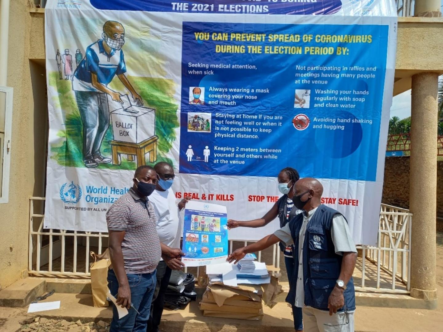 WHO officials handing over COVID-19 Information, Communication and Education material to election officials in Arua city. WHO officials handing over COVID-19 