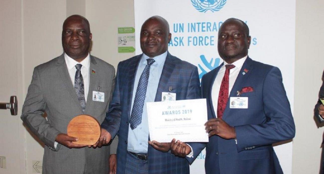 Honorable Minister of Health Jappie Mhango MP holding the UN Interagency Task Force award for NCD prevention and control