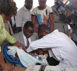 Le professeur Moustafa Mijiyawa, Ministre de la Santé et de la Protection Sociale tenant un enfant.