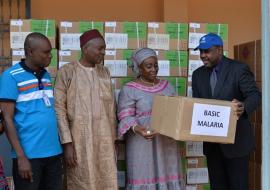 Le Représentant de lOMS remettant un échantillon de cartons de médicament à la Conseillère du Mionistre de la Santé chargée de Missions et de la Coopération