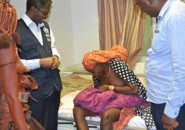 Teenage girl breastfeeding her newborn baby while WHO Representative, Dr  Charles Sagoe-Moses and Mr Thomas Shapumbu, Kunene Regional Health Director looks on