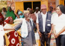 Centre (from left to right) : In light blue jacket, Baba Idris Haliru, Dr Andrew Mbewe (WHO) and Mrs Abigael Molme (Molme Foundation). Behind: Some of the beneficiaries of the intervention at Goza IDP camp. 