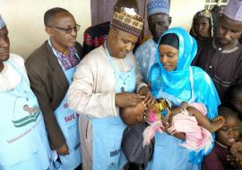 Alhaji Mohammed Abubakar (3rd left) Chairman of Tarmuwa LGA Yobe State immunizing a child during OBR flag off.