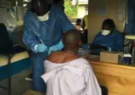 A member of the vaccinating team vaccinates a health worker in Rwebisengo