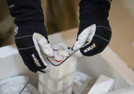 A worker places vials in a container