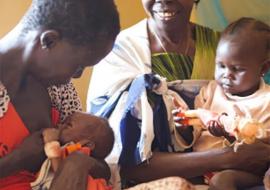 With Bakhita on her lap, Tereza encourages Ajonga to breastfeed her granddaughter, baby Akot.