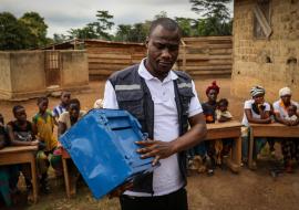 Dans le petit village de Sinkolé, situé dans la région forestière de la Guinée, des dizaines d’hommes et de femmes se rassemblent devant une salle communautaire délabrée, un vendredi matin. Marius Djo, conseiller de l’Organisation mondiale de la Santé (OMS) pour la prévention des abus et de l’exploitation sexuels (PSEA), attend que tout le monde prenne place sur de vieux bancs d’école en bois disposés en demi-cercle, puis il commence son propos par une introduction animée.