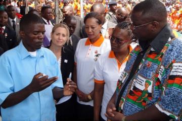 A Health Surveillance Assistant (in blue uniform) explains the procedure of preparing the Rotavirus vaccine to the Vice President as WR second from right looks on