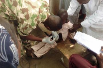 Military personnel vaccinating a child with IPV in Monguno IDP camp of Borno State