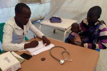 The "EWARS in a box" kit is designed with frontline health care providers in mind. Here Julius Opio, Clinical Officer in-charge with Health Link South Sudan, sees patients in Site 1 Health Facility in Mingkaman, South Sudan. Julius collects disease data from patients each day during routine consultations. If any diseases with immediate reporting requirements are seen, these can be notified immediately to the County Health Department using a mobile phone