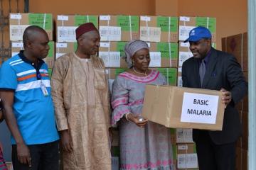 Le Représentant de lOMS remettant un échantillon de cartons de médicament à la Conseillère du Mionistre de la Santé chargée de Missions et de la Coopération