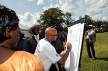 02 the who country representative dr wondimagegnehu alemu signing a leadership pledge to improve immunisation in uganda as his excellency president yoweri museveni looks on