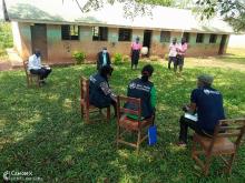 WHO team and officer from DEOs office engaging the head teacher, pupils and Askari of Kyabasara Primary School